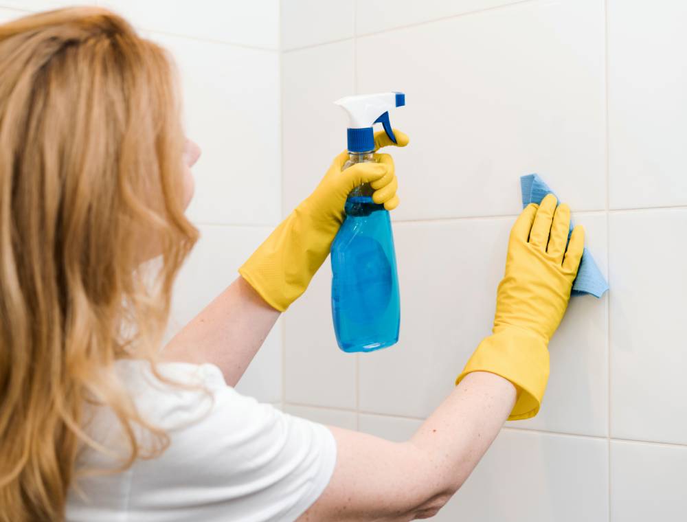Mujer limpiando para quitar moho de la ducha