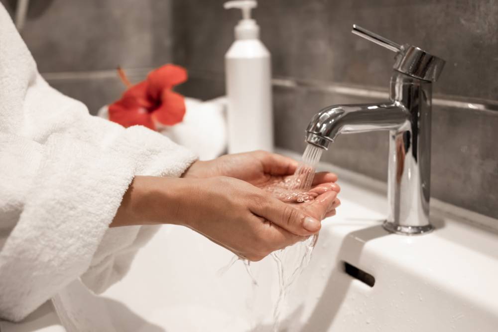 Grifo monomando de lavabo con chorro de agua sobre manos.